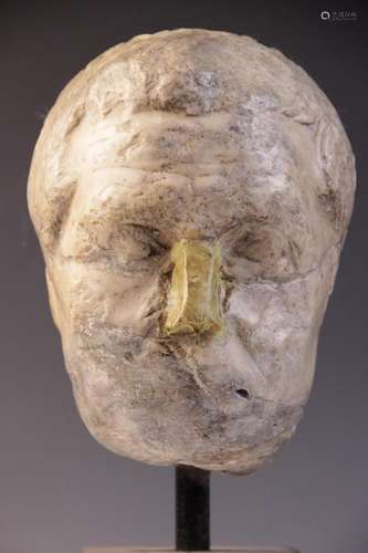 A worn marble male head carved with furrowed brow, with rest...