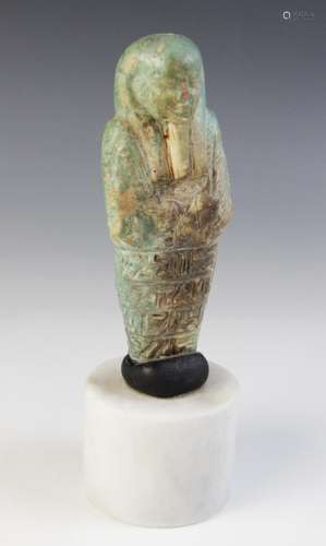 A fragmentary Egyptian green glazed faience shabti, holding ...