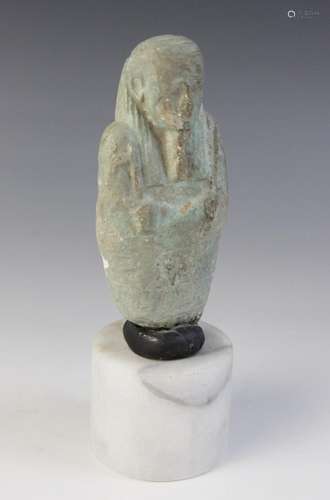 A fragmentary Egyptian blue glazed faience shabti, holding a...