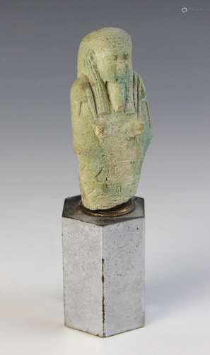 A fragmentary Egyptian green glazed faience shabti, holding ...