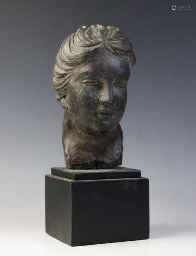 A carved stone female head, the dark coloured stone carving ...