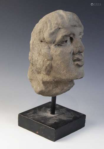 A carved stone male head, 26.5cm high, mounted upon a rod an...