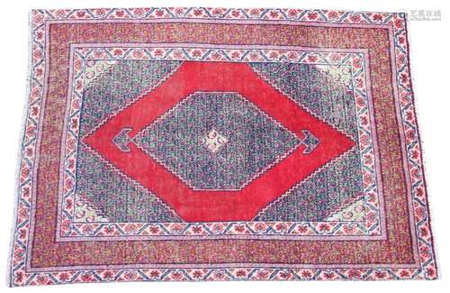 * An Iranian wool rug, the red ground with a central serrate...