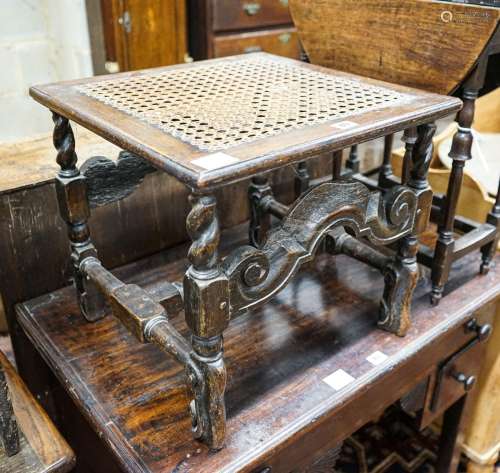 A 17th century style carved oak stool, with caned seat and H...
