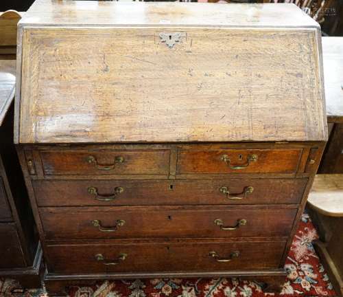 A George III oak bureau, with fitted interior, two short and...