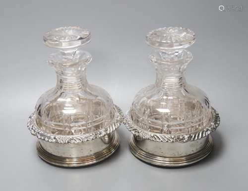 A pair of silver plated coasters with cut glass decanters. 2...