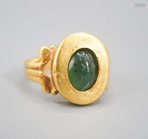 An antique yellow metal and carved nephrite? oval ring, size...