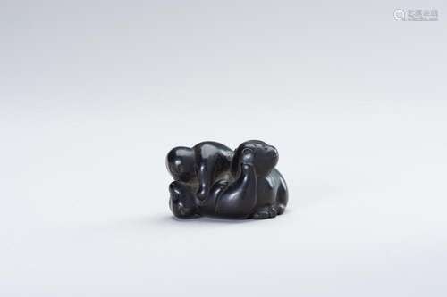 A DARK WOOD NETSUKE OF PUPPIES