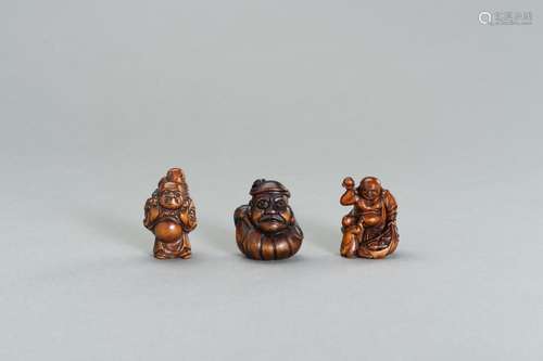 A GROUP OF THREE WOOD NETSUKE OF HOTEI AND DARUMA