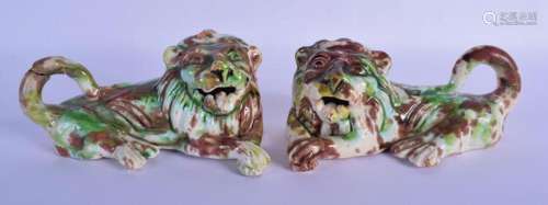 A PAIR OF GREEN AND BROWN GLAZED POTTERY LIONS modelled scow...