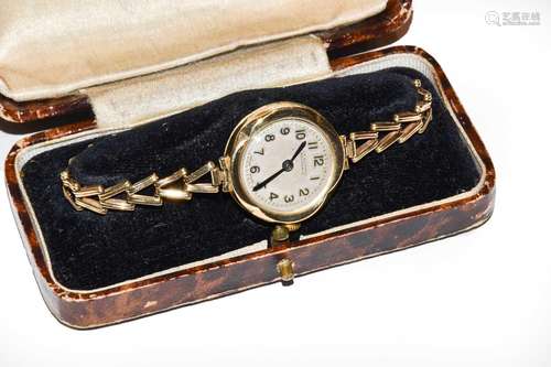 A ladys gold wristwatch; and an 18 carat gold band ring, fin...