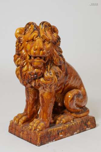 A Continental glazed earthenware model of a seated lion, pos...