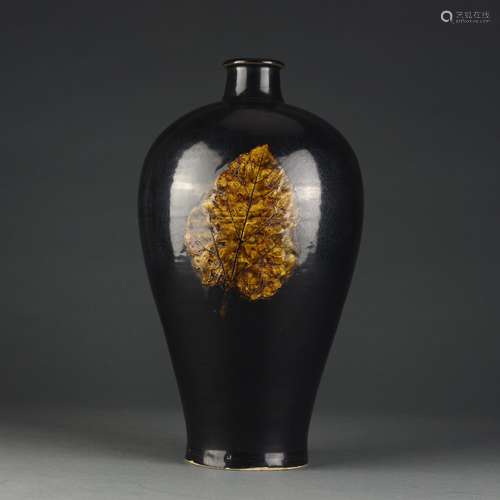 Ancient black glazed plum bottle with leaf sticking