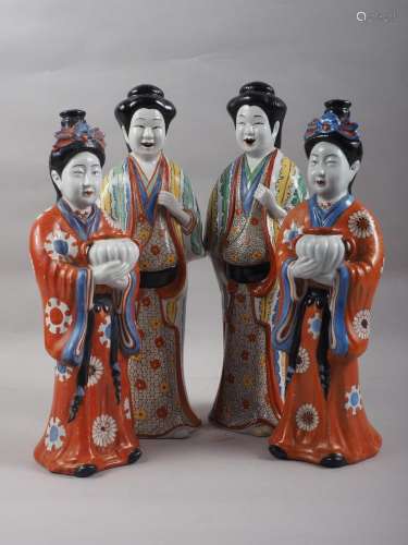 A pair of Chinese porcelain figures of women in orange robes...