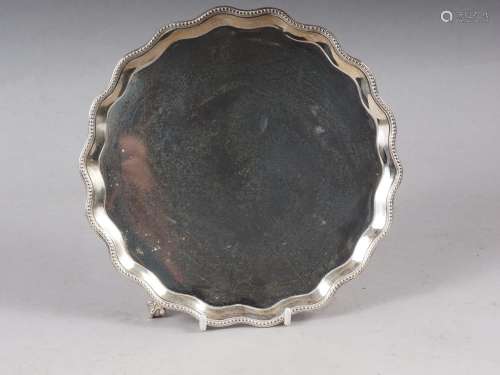 A Georgian cast silver card tray, on claw and ball supports,...