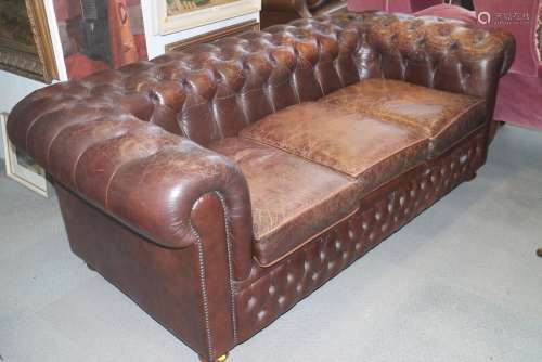 A leather chesterfield three-seat settee, button upholstered...