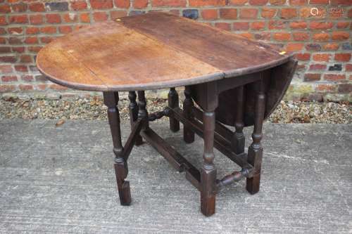 An antique oak oval top gate leg dining table, on turned and...