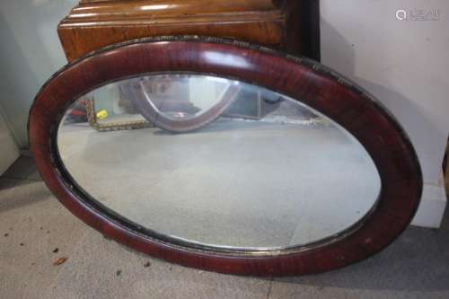 A grained as mahogany oval framed wall mirror, bevelled plat...