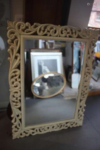 A cream painted open scrollwork framed wall mirror, bevelled...