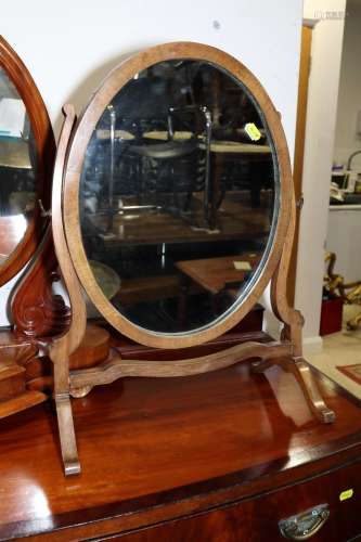 A walnut oval swing frame toilet mirror, on splay supports, ...