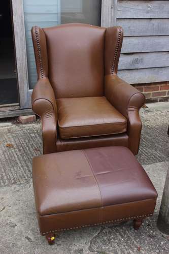 A leather wing back armchair with loose seat cushion, on tur...