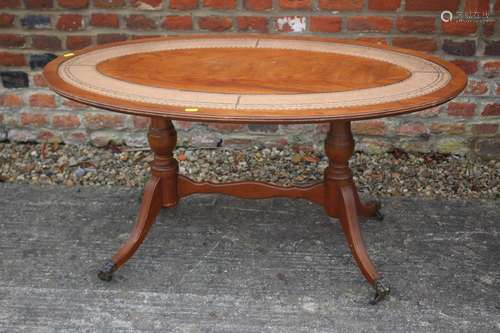 A mahogany and leather inset oval coffee table, on twin turn...