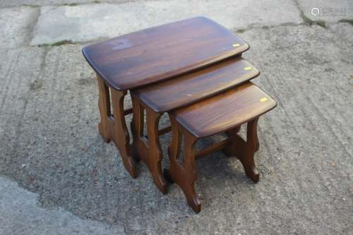 A nest of three Ercol elm occasional tables, on panel end su...