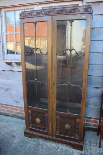 A 1930s walnut display cabinet enclosed two glazed panel doo...