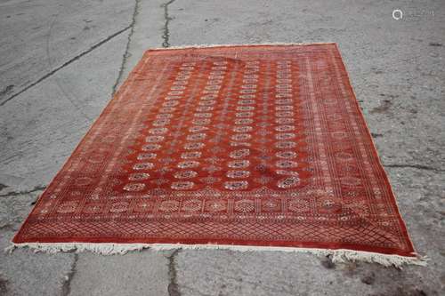 A Bokhara rug decorated seventy-six guls on a rust ground, 7...