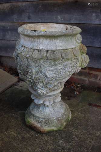 A cast stone urn with relief decoration of roses, 26 high