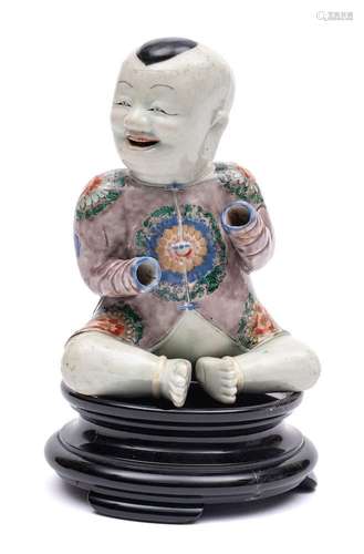 A Chinese famille verte seated figure of a smiling boy: wear...