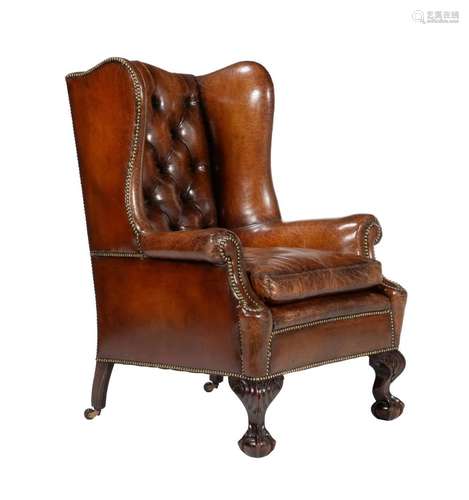 A walnut and leather buttoned wing back armchair in George I...