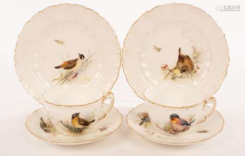 A pair of tea cups and saucers painted birds in foliage with...