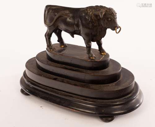 A bronze figure of a bull on a stepped oval plinth,