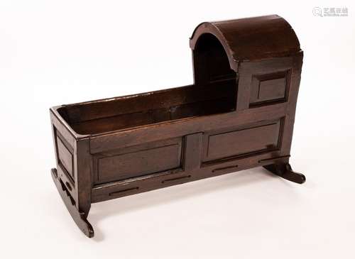 An oak cradle with an arch top hood and panelled sides, havi...