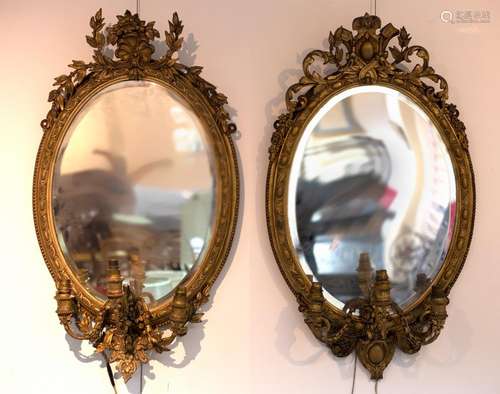 A near pair of gilt framed oval girandoles, each with scroll...