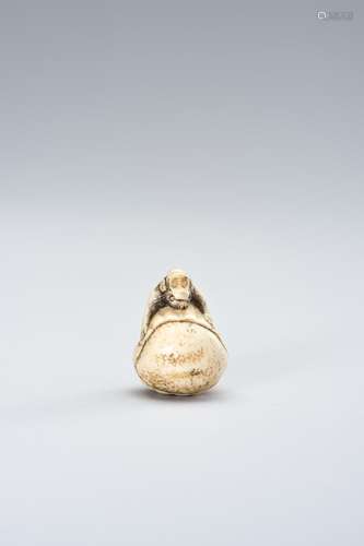 AN IVORY NETSUKE OF A MONKEY EMERGING FROM A CHESTNUT