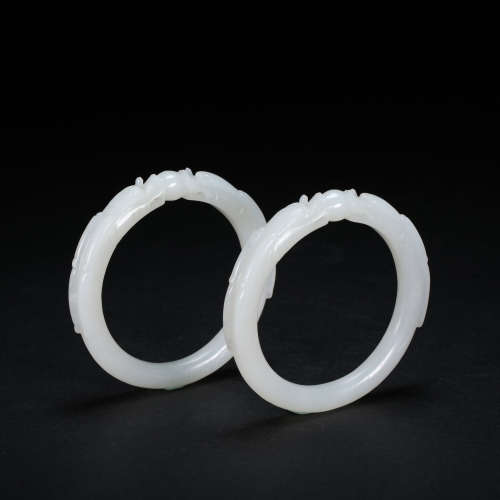 A PAIR OF CHINESE HETIAN WHITE JADE DRAGON BRACELETS, QING D...