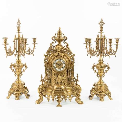 A three-piece mantle clock with candelabra made of bronze. (...