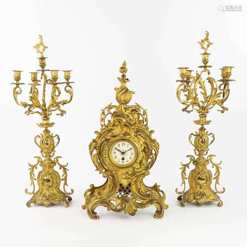 A three-piece mantle clock with 2 candelabra made of gilt br...