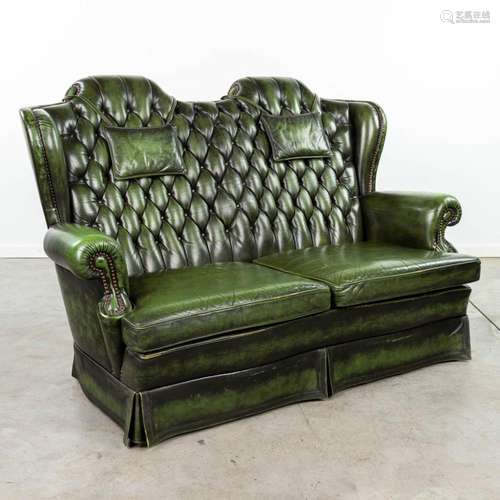 A green leather armchair with high back made in Chesterfield...