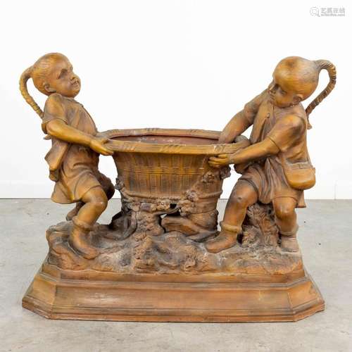 A large terracotta statue of two children and a basket, made...