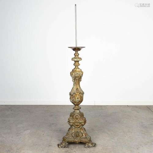 A large candlestick made of bronze and decorated with figuri...