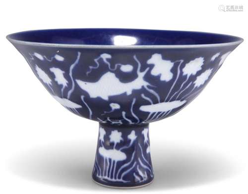 A MING-STYLE BLUE GROUND STEM CUP, decorated in white reserv...