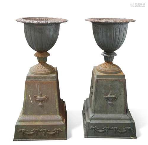 A PAIR OF CAST IRON URNS ON STANDS, each urn with leaf-cast ...