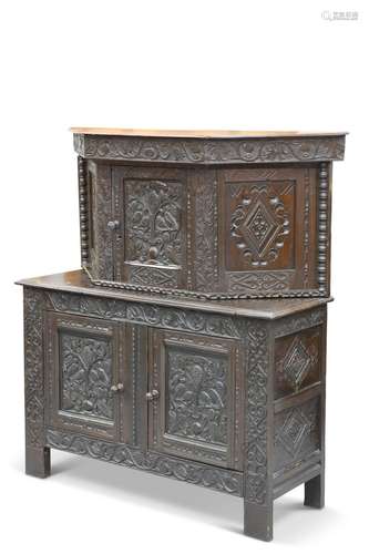 A CARVED OAK CUPBOARD, the canted upper section with a centr...