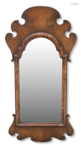 A GEORGE II-STYLE WALNUT FRETWORK MIRROR, the arched mirror-...