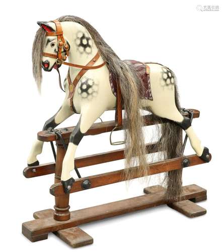 A SMALL CARVED AND PAINTED ROCKING HORSE, with harness, on s...