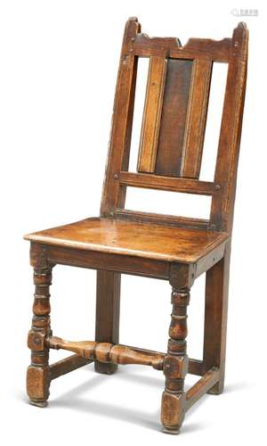 A 17TH CENTURY OAK PANEL-BACK CHAIR, raised on block and bal...