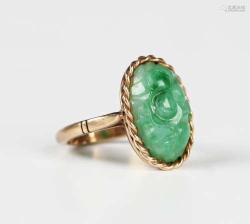 A gold and jade ring, the oval jade with carved decoration w...